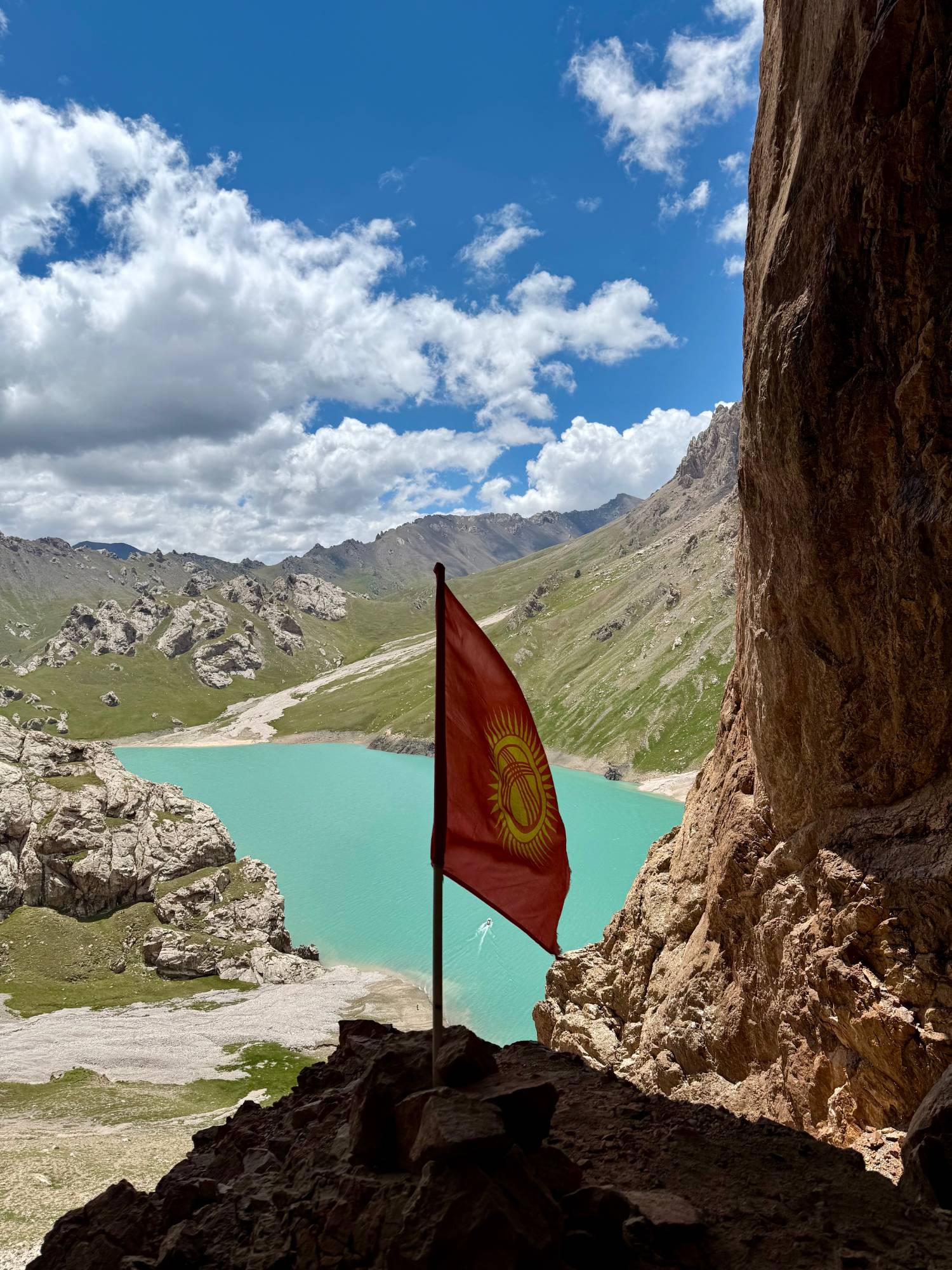 Drapeau kirghize devant un lac turquoise entouré de montagnes