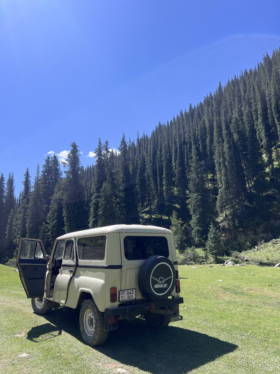 4x4 UAZ garé au pied d'une forêt de sapins